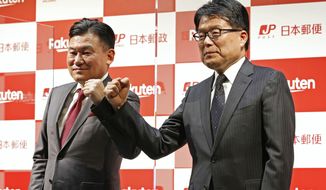 Japan Post Holdings President Hiroya Masuda, right, and Rakuten President Hiroshi Mikitani, left, pose together during a press conference on their strategic partnership on Dec. 24, 2020 in Tokyo. Japan’s giant postal system said Friday, March 12, 2021, it is investing about $1.4 billion, for an 8% stake in the e-commerce venture Rakuten to strengthen a partnership in deliveries, fintech and other areas.(Sadayuki Goto/Kyodo News via AP)
