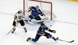 Vegas Golden Knights&#39; Alex Tuch (89) watches as the game-winning goal by teammate Reilly Smith, not shown, slips past St. Louis Blues goaltender Jordan Binnington (50) and Niko Mikkola (77) during overtime of an NHL hockey game Friday, March 12, 2021, in St. Louis. (AP Photo/Jeff Roberson)