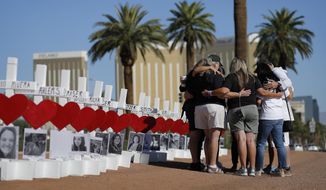 FILE - In this Oct. 1, 2019, file photo, people pray at a makeshift memorial for shooting victims in Las Vegas, on the anniversary of the mass shooting two years earlier. A panel planning a permanent memorial to the October 2017 shooting on the Las Vegas Strip made a nationwide call on Monday, March 1, 2021, for ideas about how best to remember the 58 people killed and thousands affected by the deadliest massacre in modern U.S. history. (AP Photo/John Locher, File)