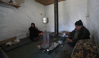 A Syrian displaced man Mohammed Zakaria, 53, who fled his Syrian hometown of Homs in 2012, prepares a hot drink as he sits inside his tent with his wife, left, at a refugee camp, in Bar Elias, in eastern Lebanon&#39;s Bekaa valley, Friday, March 5, 2021. Nearly ten years later, the family still hasn&#39;t gone back and Zakaria is among millions of Syrians unlikely to return in the foreseeable future, even as they face deteriorating living conditions abroad. The Syrian conflict has resulted in the largest displacement crisis since World War II. (AP Photo/Hussein Malla)
