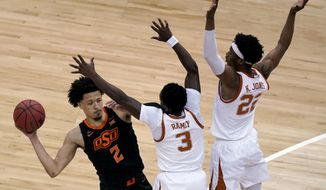 Oklahoma State&#39;s Cade Cunningham looks to pass under pressure from Texas&#39;s Kai Jones (22) and Courtney Ramey (3) during the first half of an NCAA college basketball game for the Big 12 tournament championship in Kansas City, Mo, Saturday, March 13, 2021. (AP Photo/Charlie Riedel)