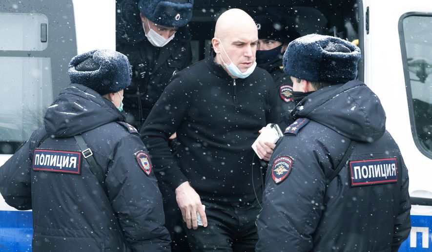 A man stands near a police bus after he was detained in Moscow, Russia, Saturday, March 13, 2021. Russian police on Saturday detained about 150 participants of a forum of independent members of municipal councils, an action that comes amid the authorities' multi-pronged crackdown on dissent. Police showed up at the gathering in Moscow shortly after it opened, saying that all those present will be detained for taking part in an event organized by an "undesirable" organization. (AP Photo/Victor Berezkin)