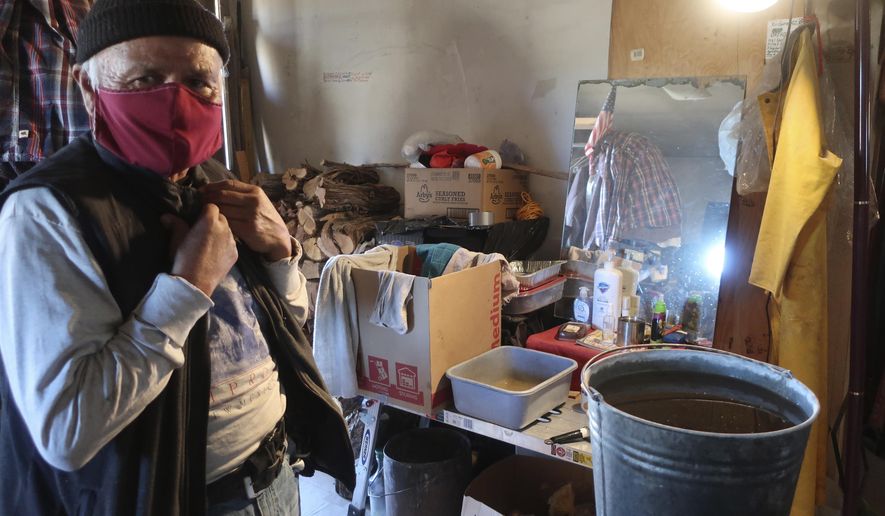 Raymond Clark stands in front of his makeshift washing station in his home in Teesto, Arizona, on the Navajo Nation on Thursday, Feb. 11, 2021. Teesto workers, health representatives, volunteers and neighbors keep close tabs on another to ensure the most vulnerable citizens get the help they need. (AP Photo/Felicia Fonseca)