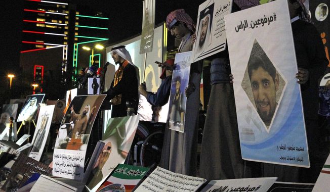 FILE - In this Feb. 14, 2018 file photo, opposition activist Bader al-Dahoum, left, speaks amid posters that show some of those detained with a hashtag in Arabic reading, &amp;quot;With Heads Held High,&amp;quot; during a protest near Kuwait&#x27;s parliament in Kuwait City, Kuwait. On Sunday, March 14, 2021, Kuwait’s constitutional court ordered al-Dahoum expelled from parliament citing an old conviction for insulting the late emir. The move inflamed tensions between the government and legislature, revealing the limits of political freedom in the Gulf state. (AP Photo/Jon Gambrell, File)