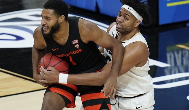 Colorado&#x27;s Evan Battey (21) tries to steal the ball from Oregon State&#x27;s Maurice Calloo (1) during the first half of an NCAA college basketball game in the championship of the Pac-12 men&#x27;s tournament Saturday, March 13, 2021, in Las Vegas. (AP Photo/John Locher)