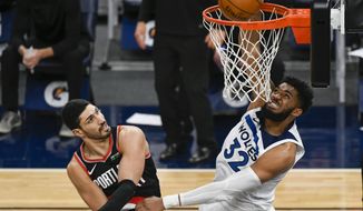Minnesota Timberwolves center Karl-Anthony Towns (32) dunks past Portland Trail Blazers center Enes Kanter during the first half of an NBA basketball game Sunday, March 14, 2021, in Minneapolis. (AP Photo/Craig Lassig)