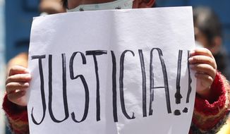 A child holds a sign reading in Spanish &amp;quot;Justice!&amp;quot; as people protest against Bolivia&#39;s former Interim President Jeanine Anez outside the police station where she is being held in La Paz, Bolivia, Sunday, March 14, 2021. Anez, who led Bolivia for a year, was arrested Saturday as officials of the restored leftist government pursue those involved in the 2019 ouster of socialist leader Evo Morales, which they regard as a coup, and the administration that followed. (AP Photo/Juan Karita)