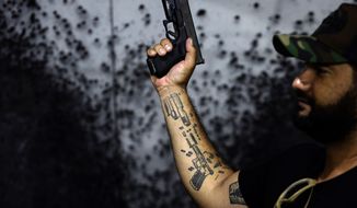 Shooting range owner Wemerson Alkmim poses for a photo showing off his gun tattoos at his Valparaiso Shooting Club on the outskirts of Brasilia, Brazil, Saturday, March 6, 2021. Brazilian President Jair Bolsonaro is pushing to deliver on his promise to arm every person that wants it. His newly-issued gun decrees, which will take effect in April unless congress or courts intervene, worry public security analysts, but excite his base. (AP Photo/Eraldo Peres)