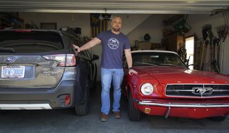 Steve Bock stands between his new Subaru Outback and his 1965 Ford Mustang at his home in Apex, N.C., on Friday, March 5, 2021. He would like to have an electric car, but says the prices will have to come down a lot before he can do it. Opinion polls show that most Americans would consider an EV if it cost less, if more charging stations existed and if a wider variety of models were available. (AP Photo/Allen G. Breed)