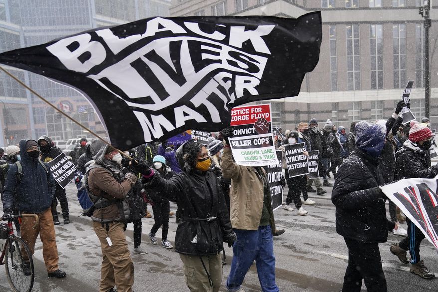 A group of protesters march in the snow around the Hennepin County Government Center, Monday, March 15, 2021, in Minneapolis where the second week of jury selection continues in the trial for former Minneapolis police officer Derek Chauvin. Chauvin is charged with murder in the death of George Floyd during an arrest last may in Minneapolis. (AP Photo/Jim Mone)