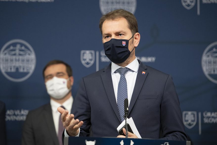 Prime Minister Igor Matovic, front, announces the resignation of Health Minister Marek Krajci, left, in Bratislava, Thursday March 11, 2021. Two parties in Slovakia’s ruling coalition called Monday March 15, 2021, on populist prime minister Matovic to step down amidst a government crisis triggered two weeks ago by a secret deal to acquire Russia’s Sputnik V coronavirus vaccine, orchestrated by Matovic. (Pavel Neubauer/TASR via AP)