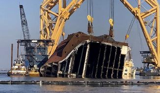 In this Feb. 25, 2021 photo, a towering crane straddles the capsized cargo ship Golden Ray, its interior decks exposed after the ship&#39;s bow was cut off and hauled away, off the coast of St. Simons Island, Ga. Salvage crews began Nov. 6 cutting the ship into giant chunks for removal. The vessel has been beached on its side since it overturned Sept. 8, 2019, soon after leaving port. (St. Simons Sound Incident response photo by Farrell Lafont of Gallagher Marine Systems via AP)
