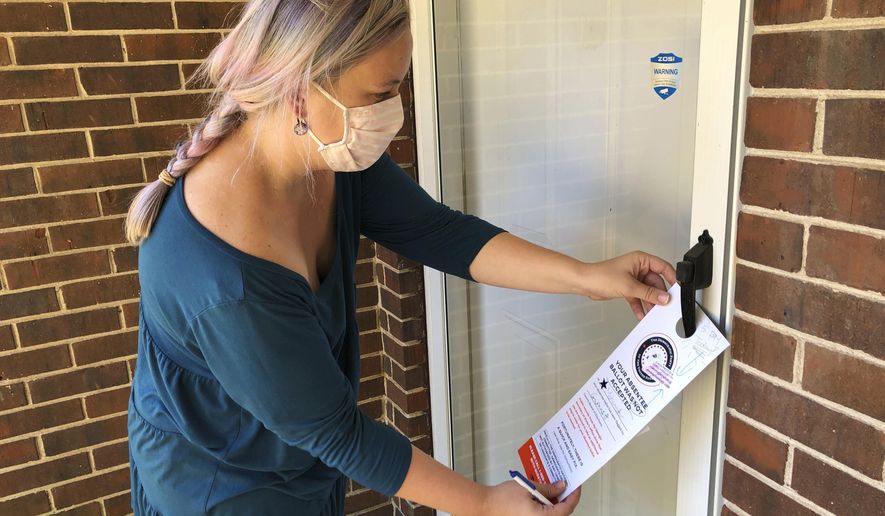FILE - In this Nov. 6, 2020, file photo, Christin Clatterbuck leaves an affidavit and information about fixing absentee ballots on the door of a home in Stone Mountain, Ga. A surge of absentee ballots during last year's election led to concerns that a larger percentage of mailed ballots could be rejected for arriving past the deadline, not having a voter's signature or some other reason. An analysis by The Associated Press shows that didn't happen. (AP Photo/Sudhin Thanawala, File)