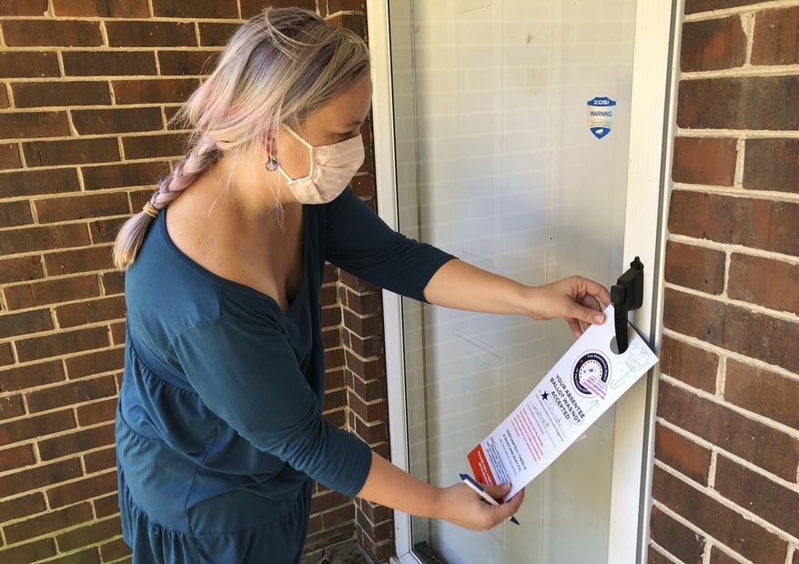 FILE - In this Nov. 6, 2020, file photo, Christin Clatterbuck leaves an affidavit and information about fixing absentee ballots on the door of a home in Stone Mountain, Ga. A surge of absentee ballots during last year's election led to concerns that a larger percentage of mailed ballots could be rejected for arriving past the deadline, not having a voter's signature or some other reason. An analysis by The Associated Press shows that didn't happen. (AP Photo/Sudhin Thanawala, File)