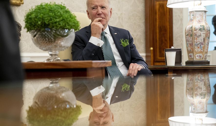 President Joe Biden sits next to a bowl of Irish shamrocks, left, as he has a virtual meeting with Ireland's Prime Minister Micheal Martin on St. Patrick's Day, in the Oval Office of the White House, Wednesday, March 17, 2021, in Washington. (AP Photo/Andrew Harnik)