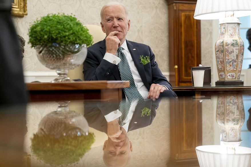 President Joe Biden sits next to a bowl of Irish shamrocks, left, as he has a virtual meeting with Ireland's Prime Minister Micheal Martin on St. Patrick's Day, in the Oval Office of the White House, Wednesday, March 17, 2021, in Washington. (AP Photo/Andrew Harnik)