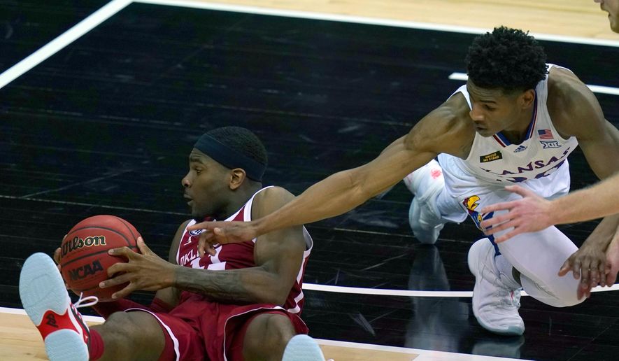 Oklahoma guard De'Vion Harmon (11) hits the floor while covered by Kansas guard Ochai Agbaji (30) during the second half of an NCAA college basketball game in the quarterfinal round of the Big 12 men's tournament in Kansas City, Mo., Thursday, March 11, 2021. Kansas defeated Oklahoma 69-62. (AP Photo/Orlin Wagner)