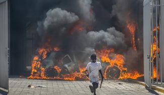 A boy runs out from the Nissan auto dealership set ablaze during a protest by a disgruntled sector of the Haitian police force known as Fantom 509, in Port-au-Prince, Haiti, Wednesday, March 17, 2021. The protests started when officers and police academy cadets marched toward police headquarters to demand that the bodies of five officers killed during a raid last week on the Village of God shantytown be recovered from the gang still holding them. Then things escalated when Fantom 509 stormed several police stations in Port-au-Prince, freeing jailed comrades accused of participating in an alleged coup against embattled President Jovenel Moise last month. (AP Photo/Dieu Nalio Chery)