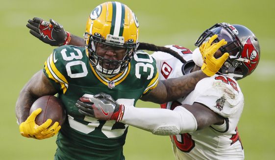 FILE - Green Bay Packers&#39; Jamaal Williams pushes off Tampa Bay Buccaneers&#39; Devin White during the second half of the NFC championship NFL football game in Green Bay, Wis., in this Sunday, Jan. 24, 2021, file photo. A person familiar with the situation says running back Jamaal Williams has agreed to sign with the Detroit Lions The person spoke Wednesday, March 21, 2021, on condition of anonymity because the team had not announced the deal. (AP Photo/Matt Ludtke, File)