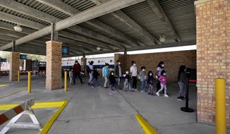 Migrants stand in line after being released from U.S. Customs and Border Protection custody at a bus station, Wednesday, March 17, 2021, in Brownsville, Texas. Team Brownsville, a humanitarian group, is helping the migrants reach their final destination in the U.S. A surge of migrants on the Southwest border has the Biden administration on the defensive. An official says U.S. authorities encountered nearly double the number children traveling alone across the Mexican border in one day this week than on an average day last month. (AP Photo/Julio Cortez)