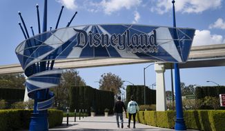 FILE - In this March 9, 2021, file photo, two visitors enter Disneyland Resort in Anaheim, Calif.  Disneyland announced Wednesday, March 17, that Disneyland and Disney California Adventure will reopen on April 30 with limited capacity. (AP Photo/Jae C. Hong, File)