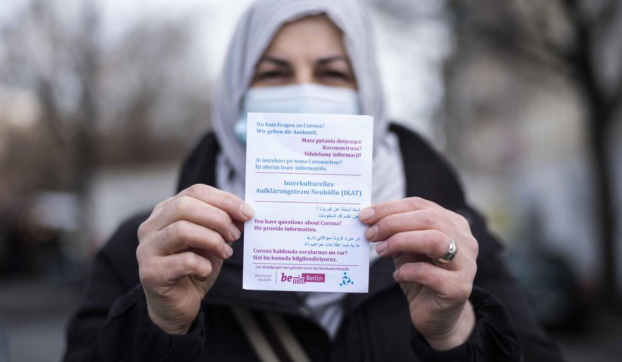 Aliye Tuerkyilmaz a member of a multilingual team of five street workers shows an information flyer as she poses for a photo in Berlin, Germany, Tuesday, March 9, 2021. Three times a week, Aliye Tuerkyilmaz hits the markets and busy shopping streets of Neukoelln, the German capital’s crowded immigrant neighborhood that’s studded with minarets, kebab stores and hookah lounges. The 48-year-old Turkish immigrant hands out flyers informing about the coronavirus pandemic and tries to connect with other immigrants in one of the four languages she speaks. Tuerkyilmaz belongs to an multilingual team, a group of five street workers trying to explain the dangers of COVID-19 to those who are often not reached through other efforts by the authorities. (AP Photo/Markus Schreiber)