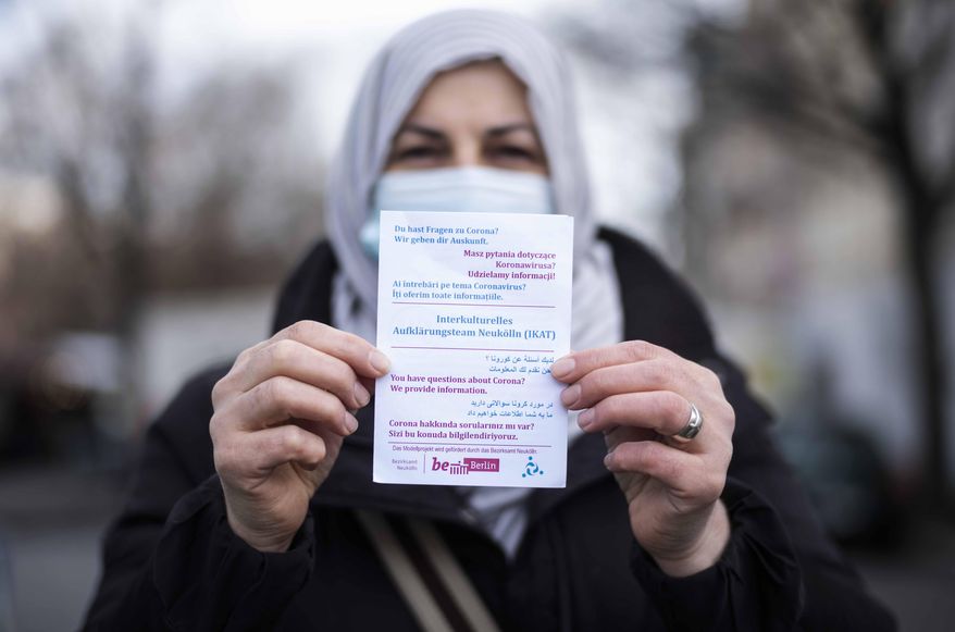 Aliye Tuerkyilmaz a member of a multilingual team of five street workers shows an information flyer as she poses for a photo in Berlin, Germany, Tuesday, March 9, 2021. Three times a week, Aliye Tuerkyilmaz hits the markets and busy shopping streets of Neukoelln, the German capital’s crowded immigrant neighborhood that’s studded with minarets, kebab stores and hookah lounges. The 48-year-old Turkish immigrant hands out flyers informing about the coronavirus pandemic and tries to connect with other immigrants in one of the four languages she speaks. Tuerkyilmaz belongs to an multilingual team, a group of five street workers trying to explain the dangers of COVID-19 to those who are often not reached through other efforts by the authorities. (AP Photo/Markus Schreiber)