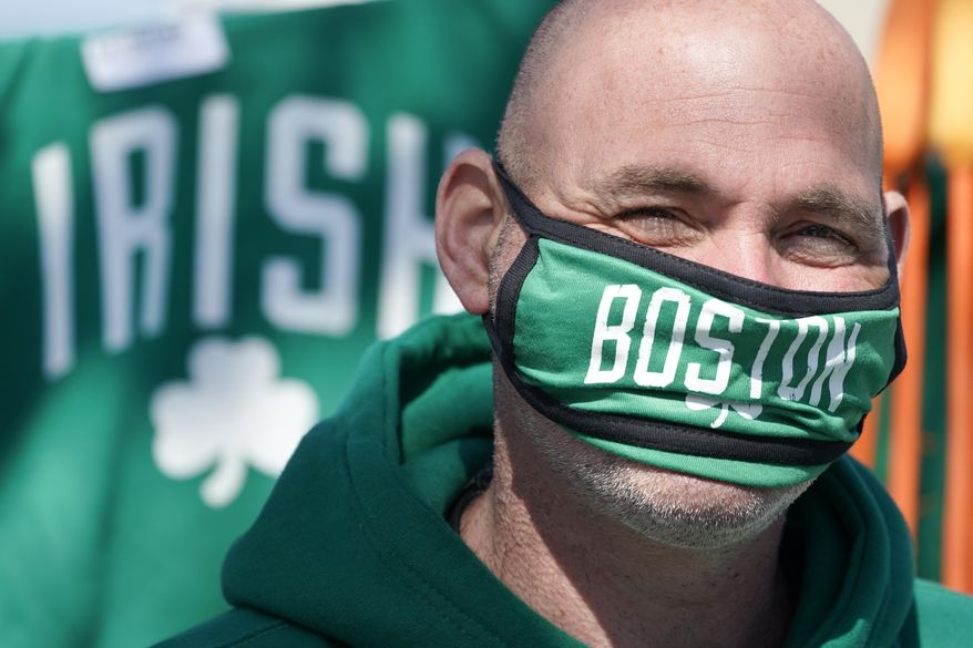 Michael Place wears a mask as he sells St. Patrick's Day merchandise, Wednesday, March 17, 2021, in South Boston. The annual St. Patrick's Day parade was cancelled for the second year in a row due to the COVID-19 pandemic. (AP Photo/Elise Amendola)