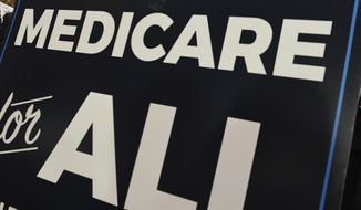 FILE - In this April 10, 2019 file photo, a sign is shown during a news conference to reintroduce &quot;Medicare for All&quot; legislation, on Capitol Hill in Washington. The Democrats’ $1.9 trillion coronavirus relief bill provides a big sweetener for the dozen states that have not expanded Medicaid under the Affordable Care Act. It dangles a larger share of federal funding over two years for the existing Medicaid population to any state that expands eligibility, a way to insure millions more Americans. Those states, all controlled by Republicans, are so far not taking the bait. Lawmakers say the expanded coverage will end up costing their state far more in the long run. (AP Photo/Susan Walsh, file)