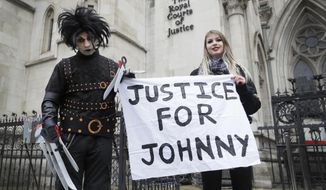Johnny Depp supporters hold a banner outside the High Court in London, Thursday, March 18, 2021. Johnny Depp&#39;s bid to overturn a damning ruling that he assaulted his ex-wife Amber Heard and put her in fear for her life will be considered by the Court of Appeal on Thursday. (AP Photo/Kirsty Wigglesworth)