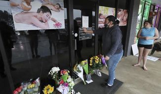 Jessica Lang pauses and places her hand on the door in a moment of grief after dropping off flowers with her daughter Summer at Youngs Asian Massage parlor where four people were killed, Wednesday, March 17, 2021, in Acworth, Ga. At least eight people were found dead at three different spas in the Atlanta area Tuesday by suspected shooter Robert Aaron Long. Lang, a local resident who lives nearby, said she knew one of the victims. (Curtis Compton/Atlanta Journal-Constitution via AP)