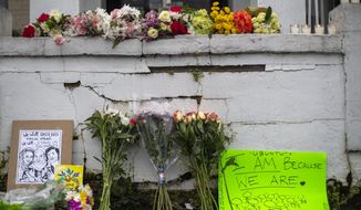 Flowers and signs are displayed at a makeshift memorial outside of the Gold Spa in Atlanta, Wednesday, March 17, 2021. Police in the Atlanta suburb of Gwinnett County say they&#39;ve begun extra patrols in and around Asian businesses there following the shooting at three massage parlors in the area that killed eight, most of them women of Asian descent. (Alyssa Pointer/Atlanta Journal-Constitution via AP)