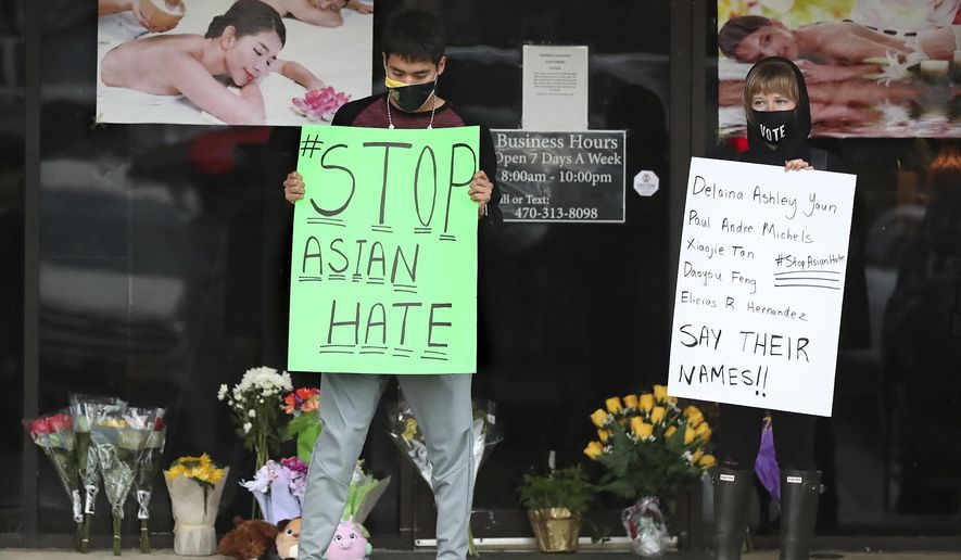 After dropping off flowers Jesus Estrella, left, and Shelby stand in support of the Asian and Hispanic community outside Young's Asian Massage Wednesday, March 17, 2021, in Acworth, Ga. Asian Americans, already worn down by a year of racist attacks fueled by the pandemic, are reeling but trying to find a path forward in the wake of the horrific shootings at three Atlanta-area massage businesses that left eight people dead, most of them Asian women. (Curtis Compton /Atlanta Journal-Constitution via AP)