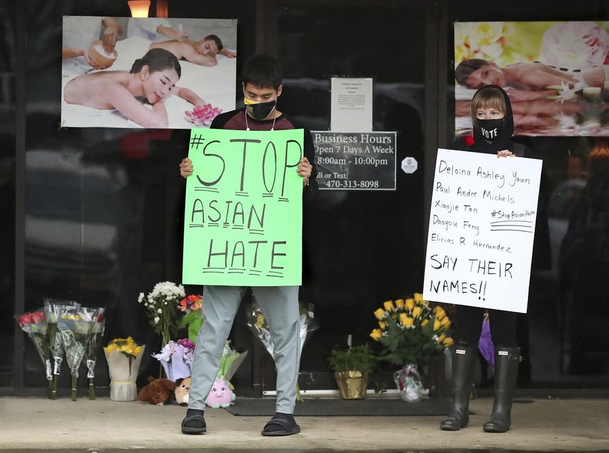 After dropping off flowers Jesus Estrella, left, and Shelby stand in support of the Asian and Hispanic community outside Young's Asian Massage Wednesday, March 17, 2021, in Acworth, Ga. Asian Americans, already worn down by a year of racist attacks fueled by the pandemic, are reeling but trying to find a path forward in the wake of the horrific shootings at three Atlanta-area massage businesses that left eight people dead, most of them Asian women. (Curtis Compton /Atlanta Journal-Constitution via AP)