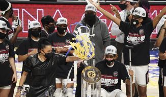 South Carolina head coach Dawn Staley puts streamers on a trophy after an NCAA college basketball game against Georgia Sunday, March 7, 2021, during the Southeastern Conference tournament final in Greenville, S.C. (AP Photo/Sean Rayford)