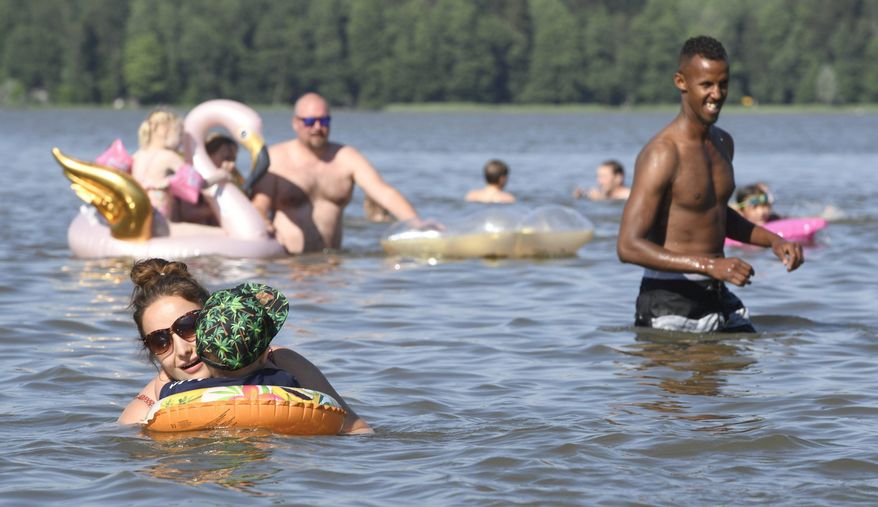 People enjoy hot summer day in a lake in Espoo, Finland, on June 26, 2020. In a year of untimely deaths from the coronavirus, economic decline and social loneliness, The World Happiness Report revealing the world’s happiest countries shows Friday March 19, 2021, Nordic countries topped the index, with Finland leading for the fourth consecutive year. (Heikki Saukkomaa/Lehtikuva via AP)