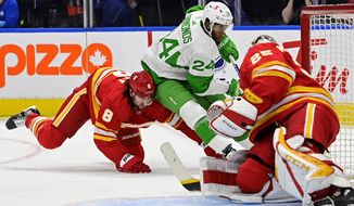 Toronto Maple Leafs right wing Wayne Simmonds (24) drives around Calgary Flames defenceman Christopher Tanev (8) as Flames goaltender Jacob Markstrom (25) defends during the first period of an NHL action in Toronto, Ontario, on Friday, March 19, 2021. (Frank Gunn/The Canadian Press via AP)