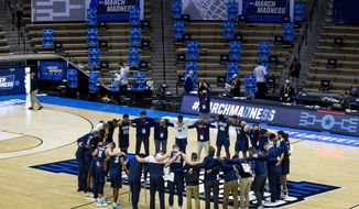Oral Roberts players and coaches form a prayer circle on the court following their win over Ohio State in a first-round game in the NCAA men&#39;s college basketball tournament, Friday, March 19, 2021, at Mackey Arena in West Lafayette, Ind. (AP Photo/Robert Franklin)