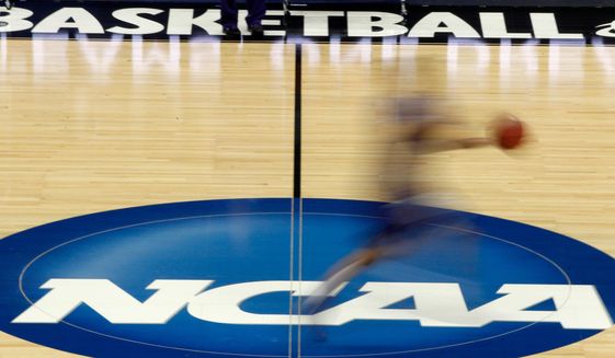 In this March 14, 2012, file photo, a player runs across the NCAA logo during practice in Pittsburgh before an NCAA tournament college basketball game. NCAA basketball administrators apologized to the women’s basketball players and coaches after inequities between the men’s and women’s tournament went viral on social media. Administrators vowed to do better. NCAA Senior Vice President of Basketball Dan Gavitt spoke on a zoom call Friday, March 19, 2021, a day after photos showed the difference between the weight rooms at the two tournaments. (AP Photo/Keith Srakocic, File) **FILE**