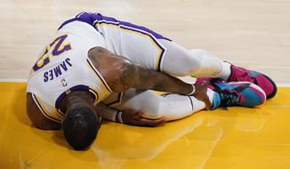Los Angeles Lakers forward LeBron James holds his ankle after going down with an injury during the first half of an NBA basketball game against the Atlanta Hawks Saturday, March 20, 2021, in Los Angeles. (AP Photo/Marcio Jose Sanchez)