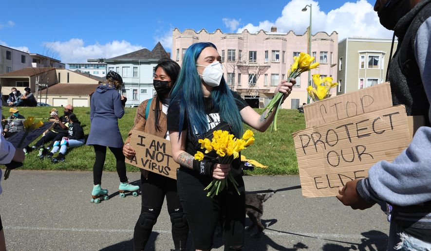 Organizer Ashley Silva distributes flowers to folks attending a rally organized in solidarity against racist violence against Asian Americans at Madison Park on Saturday, March 20, 2021 in Oakland, Calif. (Yalonda M. James/San Francisco Chronicle via AP)