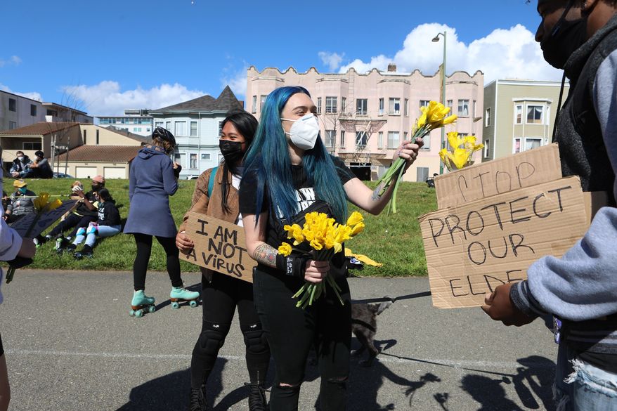 Organizer Ashley Silva distributes flowers to folks attending a rally organized in solidarity against racist violence against Asian Americans at Madison Park on Saturday, March 20, 2021 in Oakland, Calif. (Yalonda M. James/San Francisco Chronicle via AP)