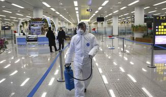FILE - In this Feb. 1, 2020, file photo, a staff member of State Commission of Quality Management in protective gear carries a disinfectant spray can as they continue to check the health of travelers in foreign countries and inspect and quarantine goods being delivered via the borders at the Pyongyang Airport in Pyongyang, North Korea. A U.N. spokesman said the world body has been left with no international staff in North Korea and its North Korean employees are working remotely. Despite claiming to be coronavirus free, North Korea has sealed off its borders as part of stringent anti-pandemic measures that also involved the departure of diplomats and foreign nationals. (AP Photo/Jon Chol Jin, File)