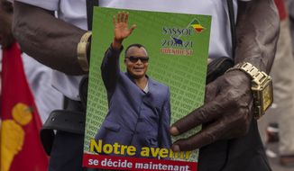A supporter of President Denis Sassou N&#39;Guesso holds his photo during the last rally of the presidential campaign in Brazzaville, Congo, Friday March 19, 2021. After 36 years in power, Republic of Congo&#39;s President Denis Sassou N’Guesso appears poised to extend his tenure as one of Africa&#39;s longest-serving leaders in the elections to be held Sunday amid opposition complaints of interference with their campaigns. (AP Photo/Zed Lebon)