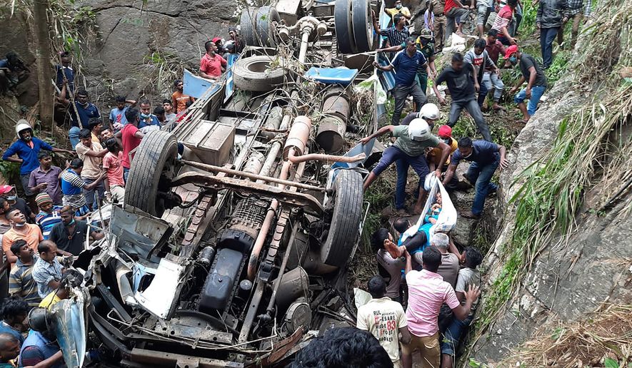 Sri Lankan police officers and rescuers lift out the body of a survivor from the debris of a bus that plunged into a precipice in Passara, about 240 kilometers east of Colombo, Sri Lanka, Saturday, March 20, 2021. A passenger bus plunged off a road in central Sri Lanka on Saturday, killing more than a dozen people and injuring more than 30. (AP Photo/Prasanna Pathmasiri)