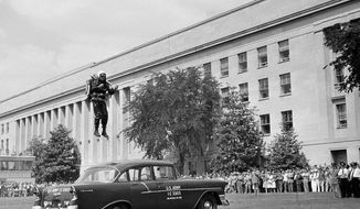 Engineer Harold Graham, of Buffalo, N.Y., glides over a parked car during a demonstration of a one-man, rocket-powered jet pack, outside of the Pentagon in Arlington, Va., June 16, 1961. The demonstration, sponsored by the Army, draws a crowd of Pentagon workers. The control tower at left is used in directing helicopter traffic to and from the Pentagon. (AP Photo/Henry Burroughs) **FILE**