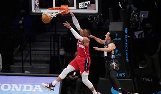 Washington Wizards guard Russell Westbrook (4) dunks with Brooklyn Nets guard Landry Shamet (20) defending during the second quarter of an NBA basketball game, Sunday, March 21, 2021, in New York. (AP Photo/Kathy Willens)