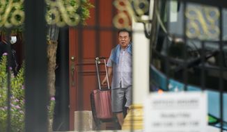 Kim Yu Song, counselor at the North Korean Embassy to Malaysia, carries his luggage into a bus at the embassy in Kuala Lumpur, Sunday, March 21, 2021. Malaysia on Friday ordered all North Korean diplomats to leave the country within 48 hours, an escalation of a diplomatic spat over Malaysia’s move to extradite a North Korean suspect to the United States on money laundering charges. (AP Photo/Vincent Thian)