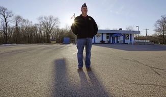 Craig DeOld, commander at Veterans of Foreign War Post #1018, stands in the post&#39;s empty parking lot as the sun sets, Monday, March 15, 2021, in Boston. Local bars and halls run by VFW and American Legion posts have fallen on hard times during the coronavirus pandemic. Organizers say many risk permanent closure after states ordered them, like other bars and halls, to shutter last spring. (AP Photo/Charles Krupa)