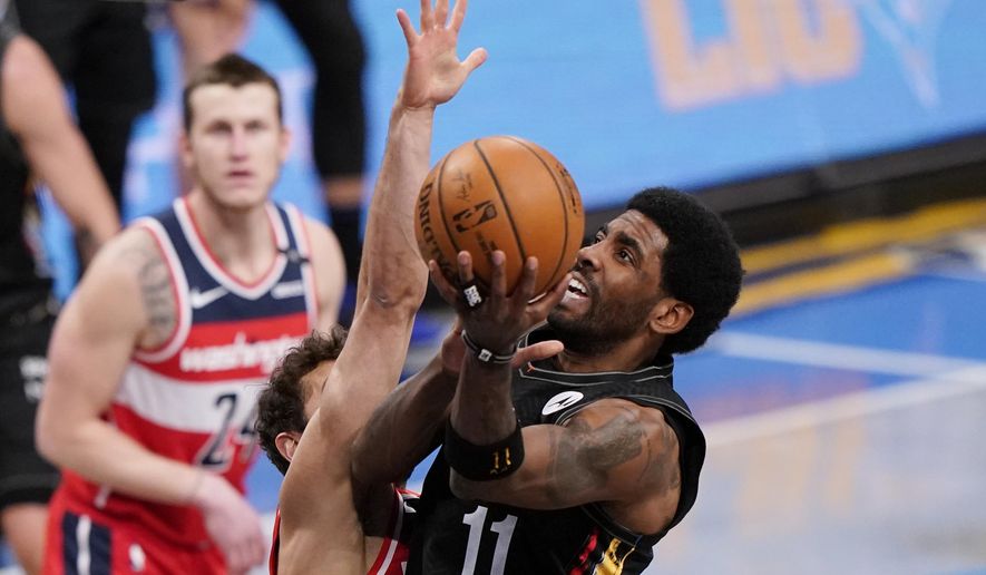 Washington Wizards guard Raul Neto defends against Brooklyn Nets guard Kyrie Irving (11) as Wizards forward Garrison Mathews (24) looks on during the first quarter of an NBA basketball game, Sunday, March 21, 2021, in New York. (AP Photo/Kathy Willens)